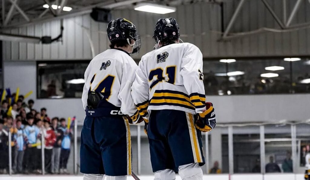 Two Mattawan hockey players stand on the blue line after being introduced at the beginning of a Michigan high school hockey game.