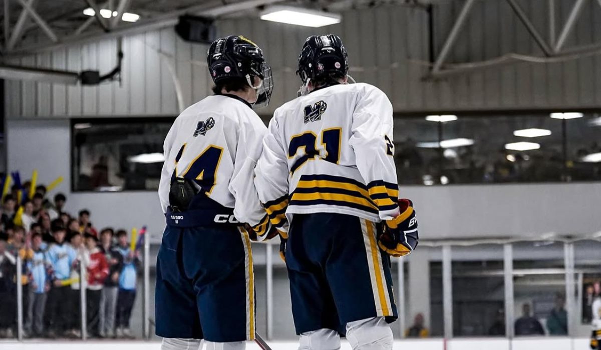 Two Mattawan hockey players stand on the blue line after being introduced at the beginning of a Michigan high school hockey game.