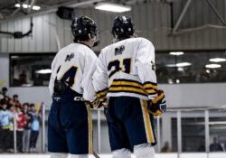 Two Mattawan hockey players stand on the blue line after being introduced at the beginning of a Michigan high school hockey game.